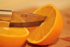nóż kuchenny przecinający pomarańczę
